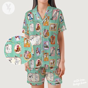 Op de afbeelding: Een mintgroene pyjamaset met een herhalend patroon van honden in feestelijke kaders. De top met korte mouwen en de shorts hebben witte biezen. De honden dragen kerstmutsen en zijn omringd door decoratieve elementen.