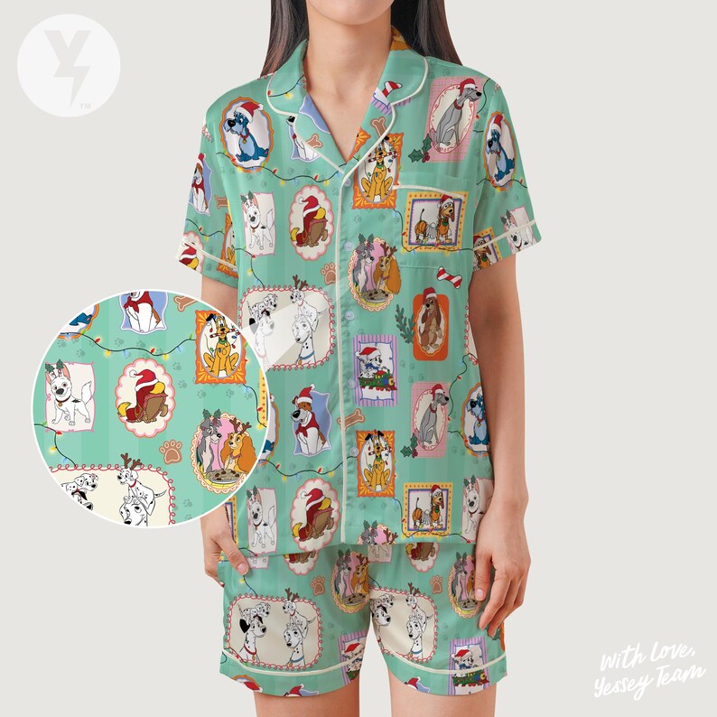 Op de afbeelding: Een mintgroene pyjamaset met een herhalend patroon van honden in feestelijke kaders. De top met korte mouwen en de shorts hebben witte biezen. De honden dragen kerstmutsen en zijn omringd door decoratieve elementen.