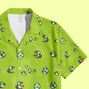 May include: Lime green button-up shirt featuring a pixelated pattern of Yoshi characters and eggs. The short-sleeved shirt has a classic collar and white buttons. The design is a vibrant, playful nod to a popular video game.
