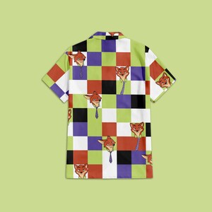 May include: Short-sleeved button-up shirt with a colorful checkerboard pattern. The shirt features a repeating cartoon fox character wearing a tie. The squares are in shades of red, green, purple, black, and white.