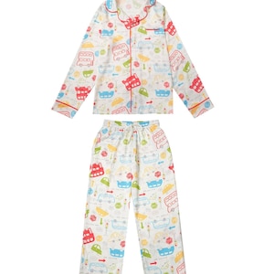 Op de afbeelding: Witte pyjamaset met een kleurrijk autopatroon. De top met lange mouwen en de broek hebben een herhalend ontwerp van bussen, auto's en verkeerslichten in rood, blauw, groen en geel. De set heeft rode biezen en een taille met trekkoord.