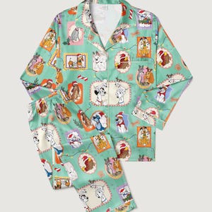 Op de afbeelding: Lichtgroene tweedelige pyjamaset met een herhalend patroon van verschillende hondenrassen in feestelijke kaders. De pyjama heeft witte biezen en een overhemd met knopen en kraag.