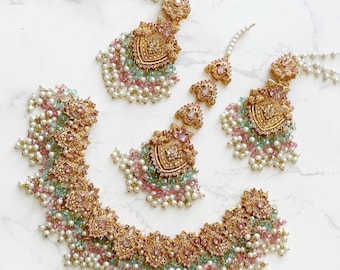 May include: A gold-toned jewelry set featuring a necklace, earrings, and headpiece. The pieces are adorned with pink, green, and white beads, and intricate gold filigree details. The set is designed for special occasions.