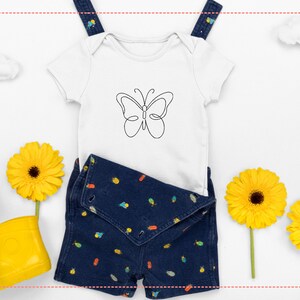 May include: A white baby onesie with a black butterfly outline design, paired with denim shorts featuring colorful illustrations. The ensemble is set against a white backdrop with yellow flowers and a pair of yellow rain boots.