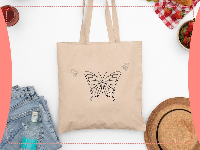 May include: Beige tote bag featuring a large black butterfly outline in the center, with two smaller butterfly outlines on either side. The bag has two handles and is made of a light-colored fabric. The design is simple and elegant.