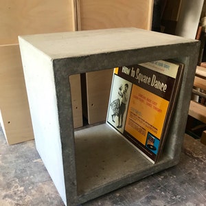 May include: A concrete cube shelf with a vintage record titled "How to Square Dance" inside. The record cover features a couple dancing and the text "Dancing Made Easy Learn Today... Dance Tonight!"