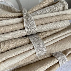 Peut inclure: Un lot d'échantillons de tissu en lin beige et crème liés ensemble par un ruban tissé beige et crème.