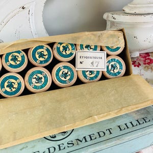 Può includere: Una scatola di legno vintage di bobine di filo con etichette blu e bianche. La scatola è etichettata "Salle-Desmedt Lille" e "Étiquetteuse N° 17".