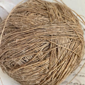 Peut inclure: Une pelote de ficelle marron naturel, étroitement enroulée avec une texture visible. La ficelle semble être faite d'un matériau fibreux, avec des brins lâches s'étendant de la boule. Idéal pour l'artisanat et l'emballage.