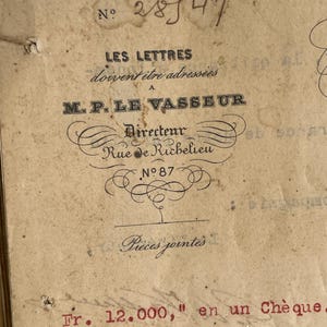 May include: Vintage paper with French text and handwritten numbers. The text includes "LES LETTRES" and "M.P. LE VASSEUR Directeur Rue de Richelieu No 87". Red text reads "Fr. 12.000," en un Chèque."