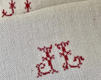 Peut inclure: Gros plan sur deux textiles en lin blanc pliés avec des initiales brodées en rouge. Les initiales "JJ" sont visibles sur les deux textiles. Le tissu a un tissage texturé.