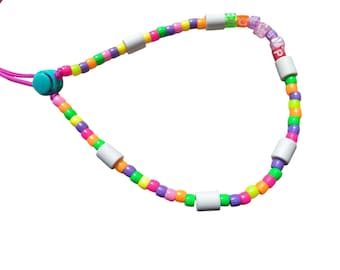 May include: A colorful beaded necklace with a pink cord and a turquoise clasp. The necklace features a variety of small, round beads in multiple colors, including pink, orange, yellow, green, purple, and white. Some beads spell out the word "LOVE".