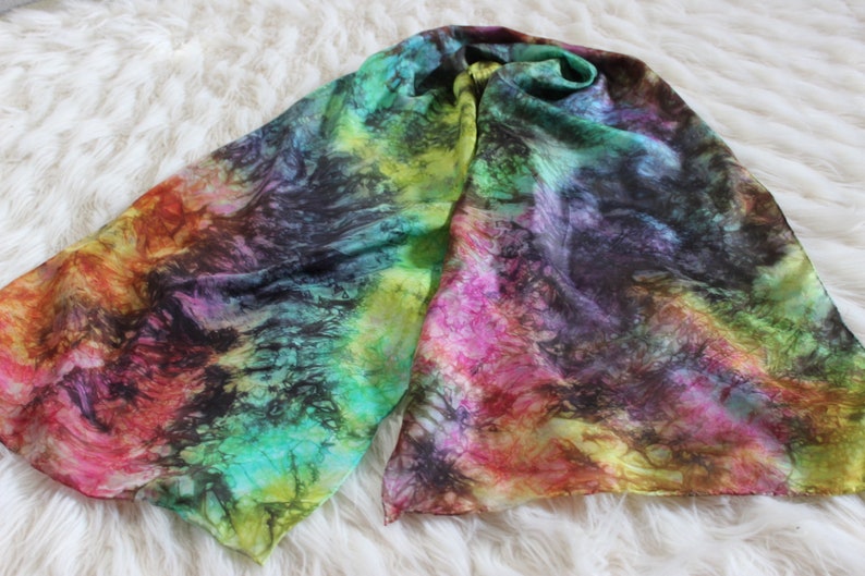 May include: A colorful silk scarf with a tie-dye pattern in shades of green, yellow, pink, red, and black.
