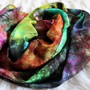 May include: A colorful silk scarf with a tie-dye pattern in shades of pink, green, yellow, orange, and brown.