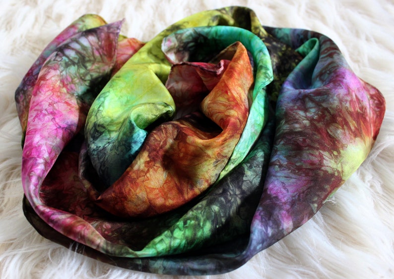 May include: A colorful silk scarf with a tie-dye pattern in shades of pink, green, yellow, orange, and brown.