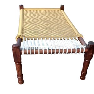 May include: A handcrafted wooden bed with a woven, diamond-patterned surface. The bed frame is dark brown, with rounded legs and a light tan woven top. The bed is designed for comfort and relaxation.