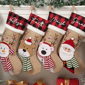 以下が含まれることがあります： アリサ、フェイス、マーシュ、サラと名前が刺繍された4つのクリスマスストッキング。各ストッキングは、赤と黒のバッファローチェックのカフス、ジュートのボディ、雪だるま、トナカイ、ホッキョクグマ、サンタクロースの顔が特徴です。ストッキングは電飾で飾られています。