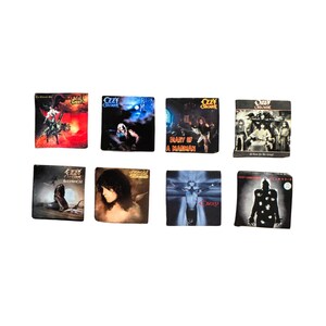 K&ouml;nnte beinhalten: Acht quadratische Magnete mit Albumcovern von Ozzy Osbourne. Die Magnete zeigen verschiedene Albumcover mit Bildern des K&uuml;nstlers, Fantasy-Szenen und Albumtiteln. Das Ozzy Osbourne-Logo ist auf mehreren Magneten zu sehen.