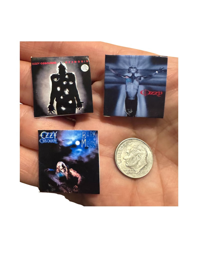 K&ouml;nnte beinhalten: Miniatur-Albumcover mit Alben von Ozzy Osbourne. Die Cover zeigen "Ozzmosis", "Ozzy" und "Bark at the Moon". Eine 10-Cent-M&uuml;nze dient als Gr&ouml;&szlig;envergleich. Die Albumcover sind quadratisch und haben dunkle und farbenfrohe Designs.
