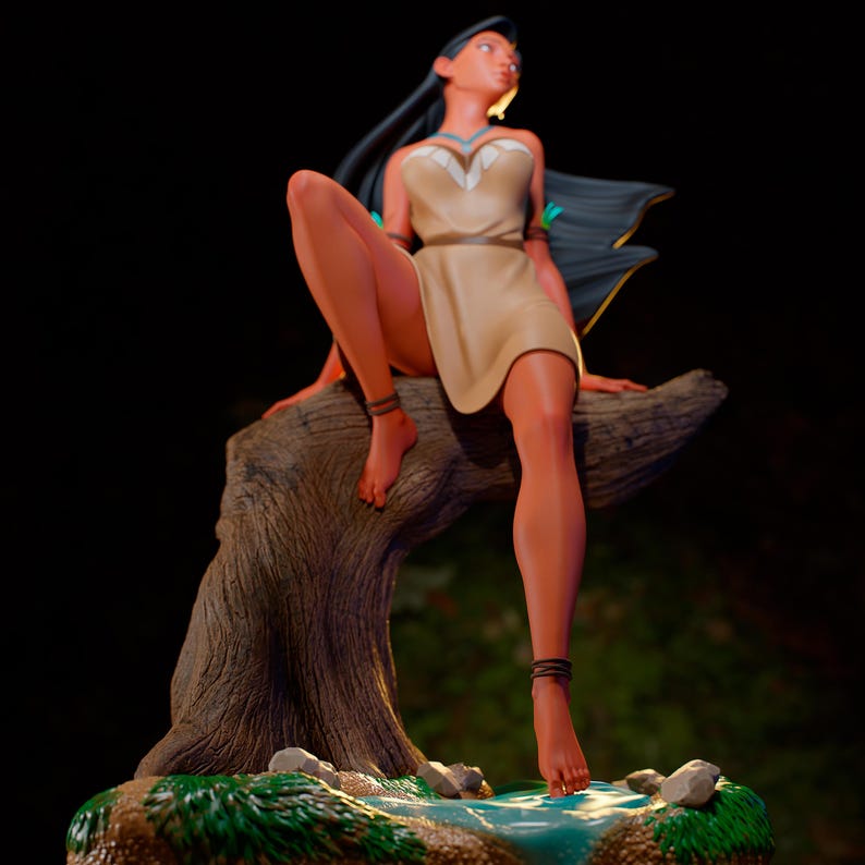 May include: A figurine of a woman with long black hair, wearing a tan dress and seated on a tree branch. The figure has a serene expression and is adorned with jewelry. The base features a small stream and rocks, with a dark background.
