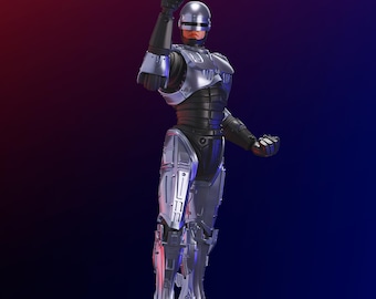 Puede incluir: Una figura detallada del personaje Robocop, en una pose dinámica con una pistola levantada. La figura es predominantemente plateada y negra, con una cara roja y un casco metálico. La base es oscura y el fondo pasa del rojo al azul. El texto "MULTI COLOR PRINTING" es visible.