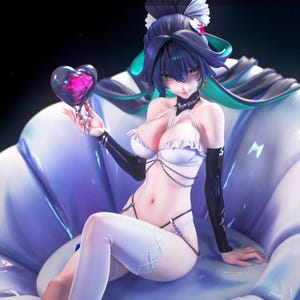 May include: A detailed anime-style figurine of a character with dark blue hair, wearing a white ruffled bikini top, black arm sleeves, and white thigh-high stockings. The figure is seated on a large, light blue shell-shaped base, holding a translucent heart-shaped object with a vibrant pink center.