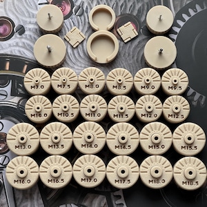 Può includere: Una collezione di componenti per orologi beige, tra cui elementi circolari con design radiali e dimensioni come M7.0, M7.5 e M8.0. Include anche piccoli quadrati e pezzi cilindrici con viti.
