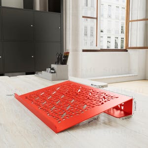 May include: A bright red metal desk organizer with a decorative floral cut-out design. The organizer is 15.7 inches wide, 10.2 inches deep, and 1.9 inches tall. It has a small lip on the front and is suitable for office or home use.