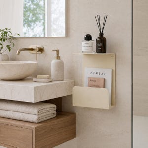 May include: A bathroom scene featuring a beige metal shelf with a magazine and perfume bottles. A marble sink, soap dispenser, and folded towels are also visible. The magazine reads "CEREAL" and "Aesop".