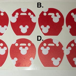 May include: A sheet of red and white stickers featuring a Mickey Mouse design. Each sticker is a red circle with white Mickey Mouse head shapes and white polka dots. The stickers are arranged in four rows of two.