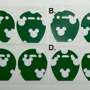 May include: Four sets of green and white decorative stickers. Each sticker is round with a slot at the top and a white Mickey Mouse head design. The stickers have a green background with white polka dots.