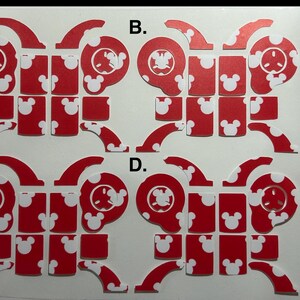 May include: Red and white die-cut stickers featuring a cartoon character design. The stickers are in multiple pieces, with a red background and white accents, including Mickey Mouse silhouettes. The design is repeated four times.