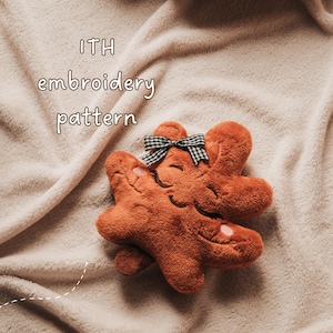 May include: A plush, rust-colored, star-shaped toy with embroidered closed eyes and a smiling mouth. It features a small black and white gingham bow at the top. The text "ITH embroidery pattern" is visible in the upper left corner of the image.
