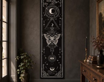 Puede incluir: Un tapiz de pared negro, alto y rectangular, con ilustraciones de líneas blancas que muestran una luna creciente, una mariposa, un triángulo geométrico, un ojo radiante y una mano sosteniendo una luna, en una composición vertical.