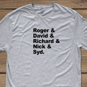 Può includere: T-shirt grigio melange con i nomi "Roger & David & Richard & Nick & Syd" stampati in nero. La maglietta ha un girocollo ed è realizzata in un tessuto morbido.