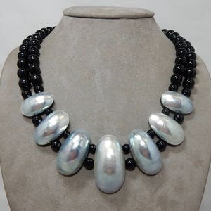 May include: A double strand necklace with black beads and a large silver pendant made of several oval shaped pearls.