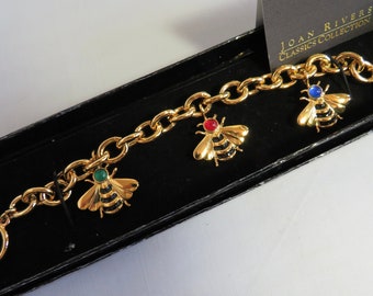 May include: A gold-tone chain link bracelet featuring three bee charms with green, red, and blue cabochon accents. The bracelet includes a toggle clasp and is presented with a card labeled JOAN RIVERS CLASSICS COLLECTION.