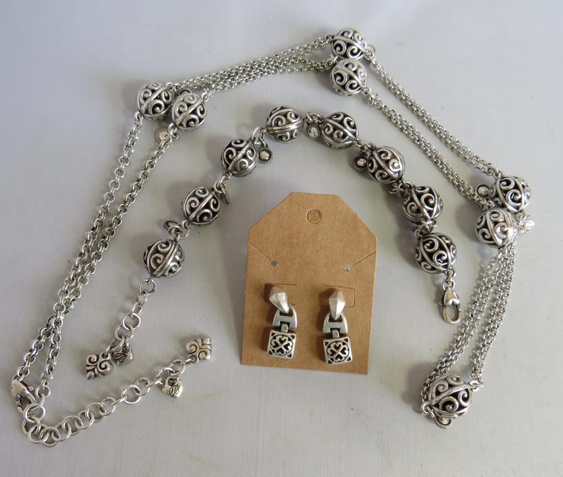 May include: A silver necklace with a chain and decorative balls, a matching bracelet, and a pair of silver earrings.
