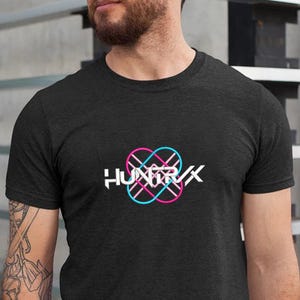 Puede incluir: Camiseta gris oscuro con el texto blanco "HUNTRX" y un logotipo rosa y azul ne&oacute;n. El logotipo es un dise&ntilde;o abstracto con formas entrelazadas. La camiseta tiene mangas cortas y cuello redondo.