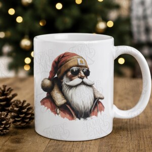 May include: A white ceramic mug featuring a graphic illustration of Santa Claus wearing a tan beanie, dark sunglasses, and a red jacket with a fur-lined collar. The design includes a watermark text that reads Family Ink across the mug surface.