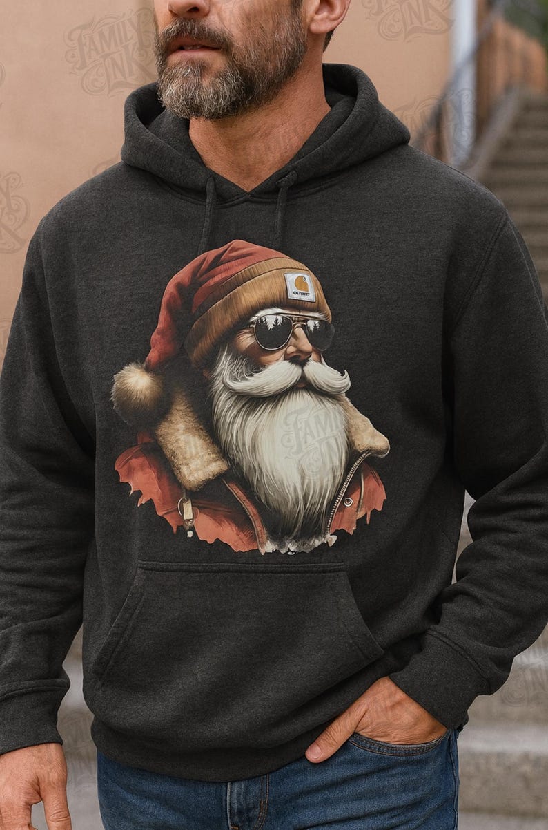 May include: A dark charcoal gray hooded sweatshirt featuring a graphic print of a bearded figure wearing a red Santa hat, a tan beanie, and dark sunglasses. The figure has a long white beard and wears a red jacket with a tan fur-lined collar.