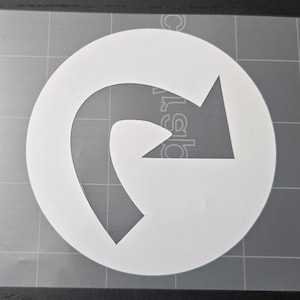 May include: White vinyl decal featuring a stylized arrow within a circle. The arrow curves back on itself, creating a unique design. The decal is on a transparent backing with a grid pattern, suitable for application on various surfaces.