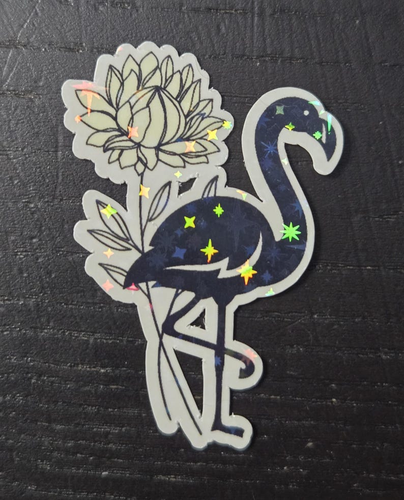 May include: A sticker featuring a stylized flamingo with a flower. The flamingo is dark blue with a starry pattern, and the flower is light green. The sticker has a holographic effect, with iridescent accents.