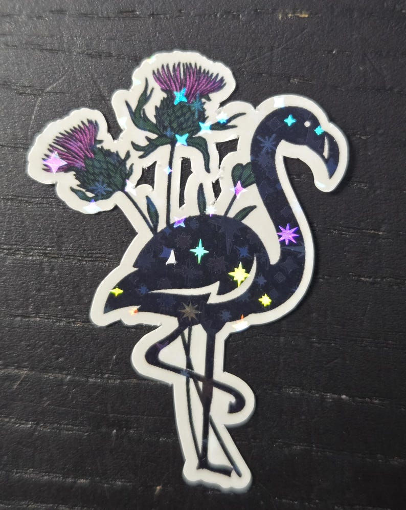 May include: A holographic sticker featuring a flamingo with a dark blue body and a white outline. The flamingo is adorned with star-shaped accents and is paired with purple thistle flowers.