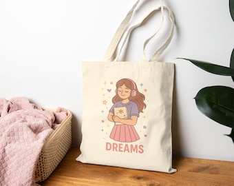 May include: Cream-colored tote bag featuring a cartoon illustration of a person wearing headphones and holding a book. The word "DREAMS" is printed in pink. The design includes stars and flowers.