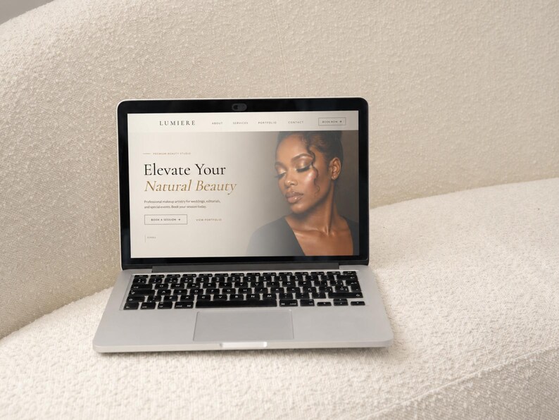 May include: A silver laptop displaying a website for Lumiere with the text Elevate Your Natural Beauty and a photograph of a person. The screen features navigation menus, a booking button, and professional makeup artist service details.