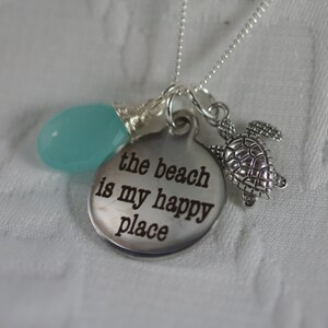 May include: Silver necklace with a round charm that says "the beach is my happy place", a turquoise gemstone, and a silver turtle charm.