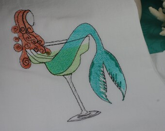 May include: Embroidered design of a mermaid with red hair sitting in a martini glass. The mermaid's tail is turquoise and green.