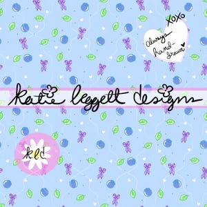 May include: A light blue pattern with blueberries, green leaves, and purple bows. The design includes the text "Katie Leggett Designs" and a heart-shaped note that says "always hand-drawn".