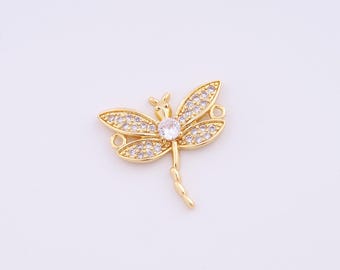 Op de afbeelding: Een goudkleurige libelle bedel met heldere, sprankelende kristallen. De libelle heeft gedetailleerde vleugels en een centrale kristal. De bedel heeft kleine lussen om aan sieraden of andere knutselwerken te bevestigen. Het ontwerp is delicaat en elegant.